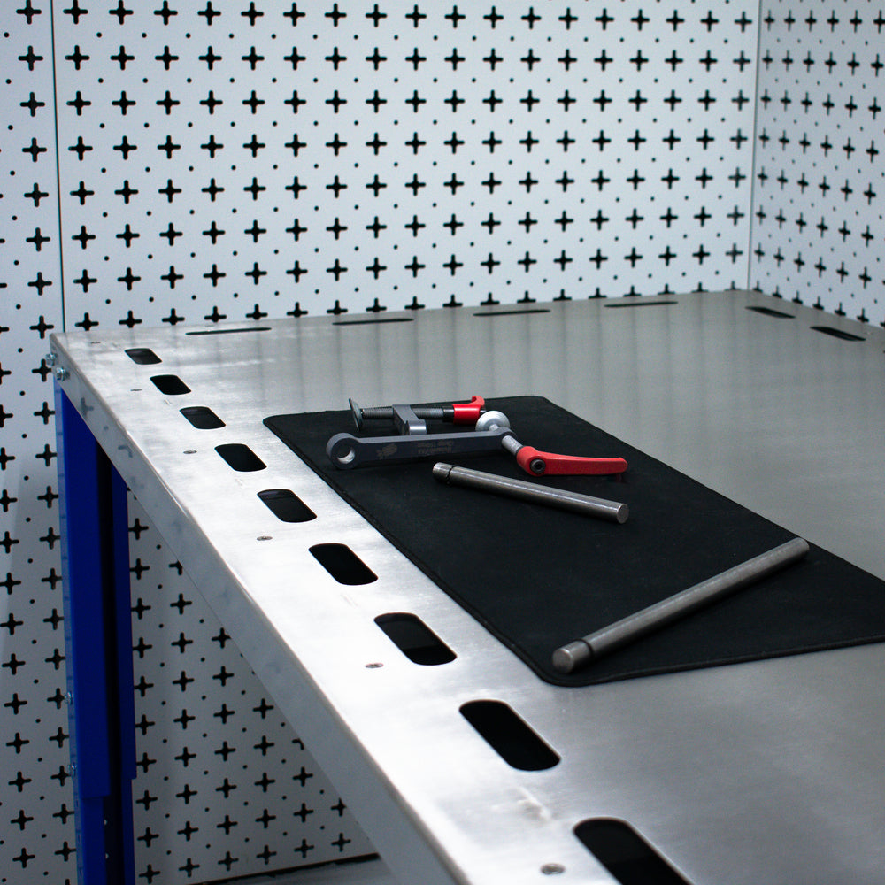 Downdraft table with tools on a black mat against a patterned wall.
