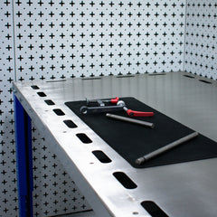 Downdraft table with tools on a black mat against a patterned wall.