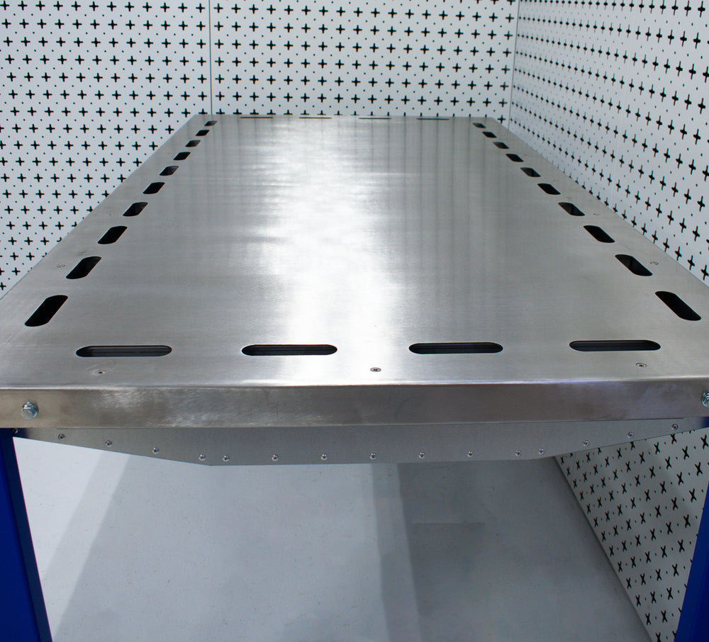Nukeson FAB custom downdraft workbench with perforated surface in a room with tiled walls.