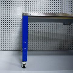Metal workbench with blue leg against a patterned wall.