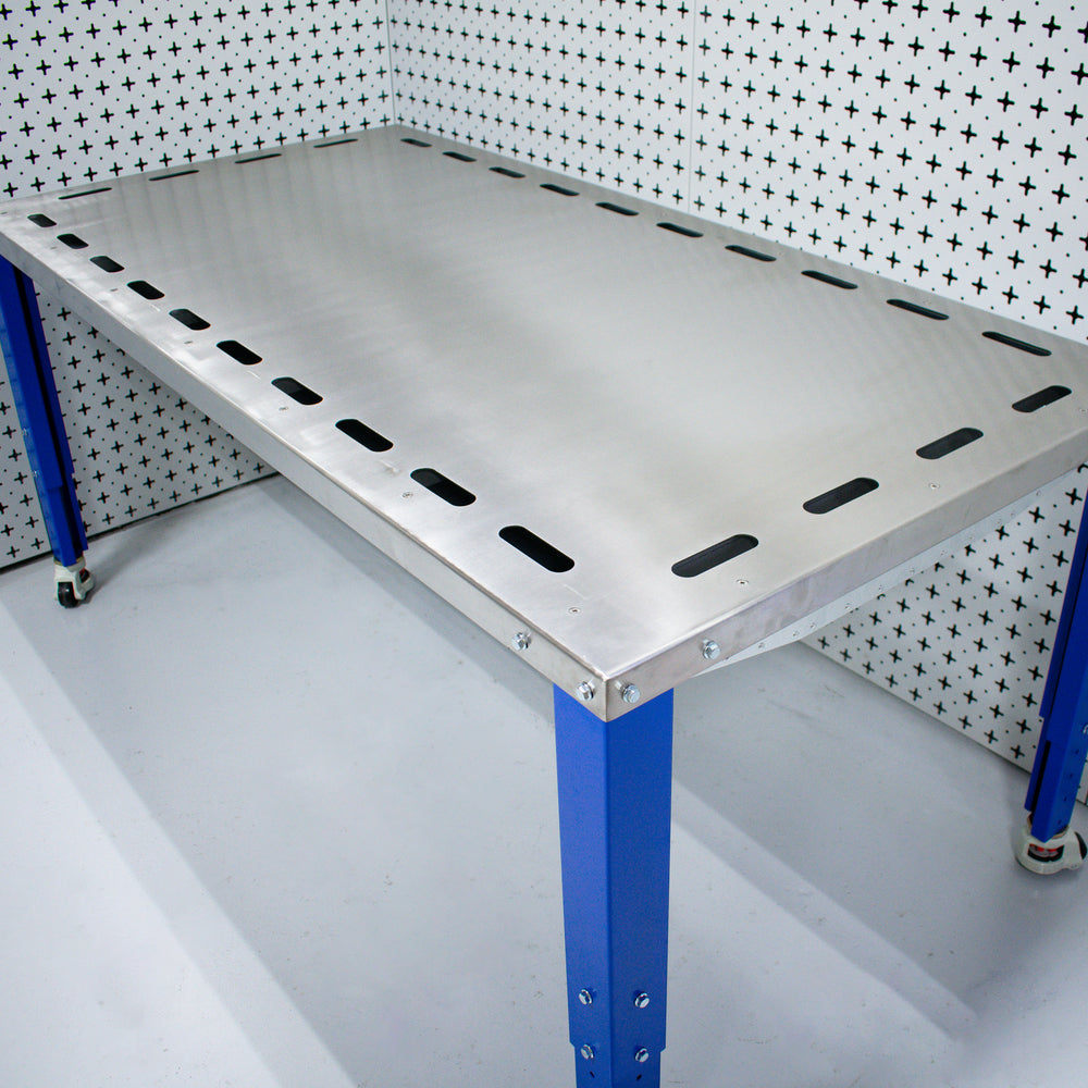 Industrial custom downdraft table workbench with blue legs against a patterned wall.