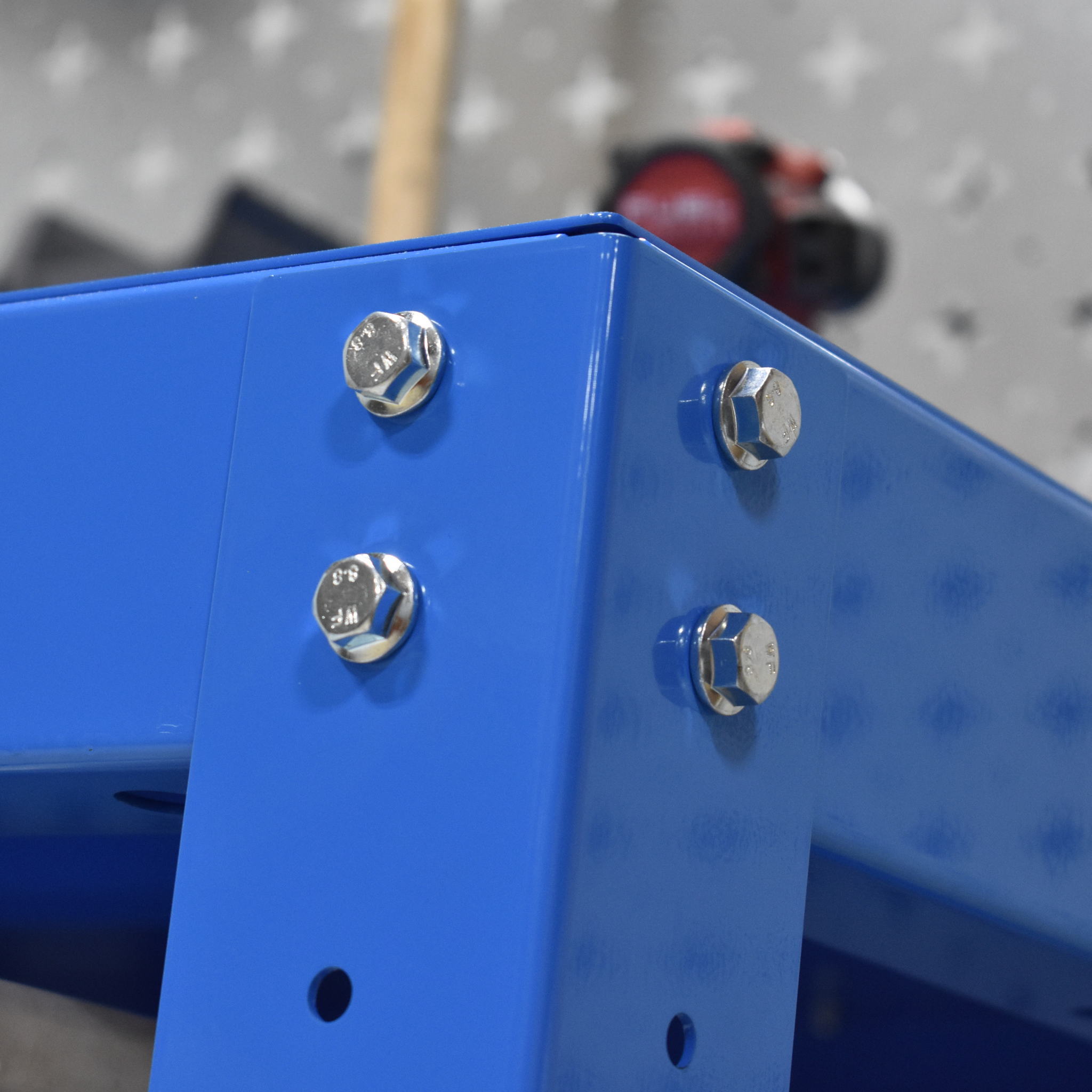 Close-up of a blue metal bracket with screws on a gray pegboard background