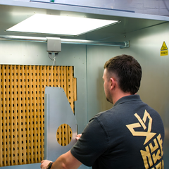 Industrial ATEX spray booth with person hanging item on the bar