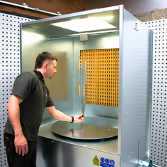 Industrial ATEX spray booth with turntable on white and black background with person hanging item