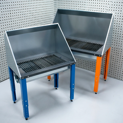 Two metal downdraft plasma cutting tables with different colour legs on a white background