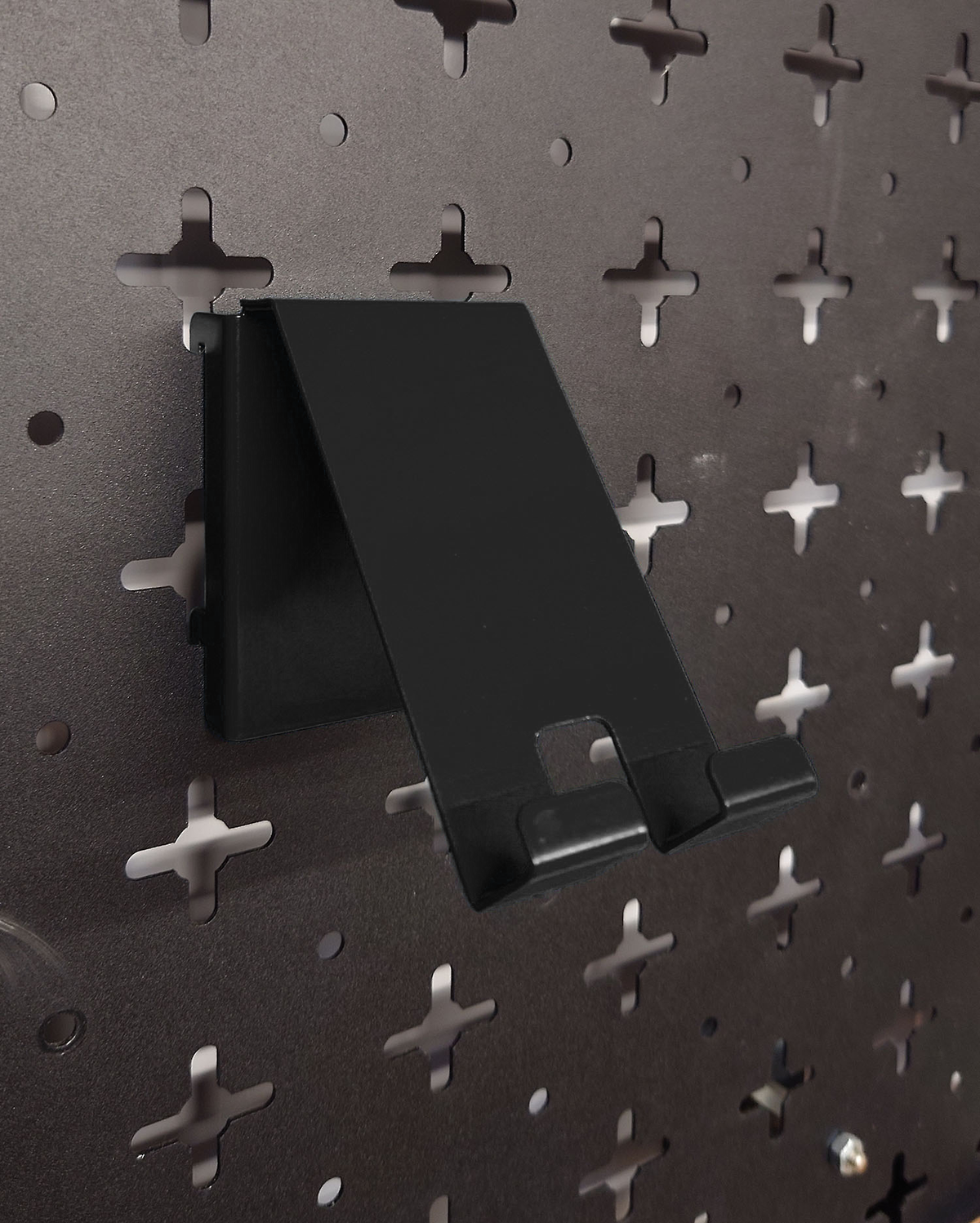 Black Nukeson Peboard Tool Wall phone holder attatchments, on a black pegboard wall