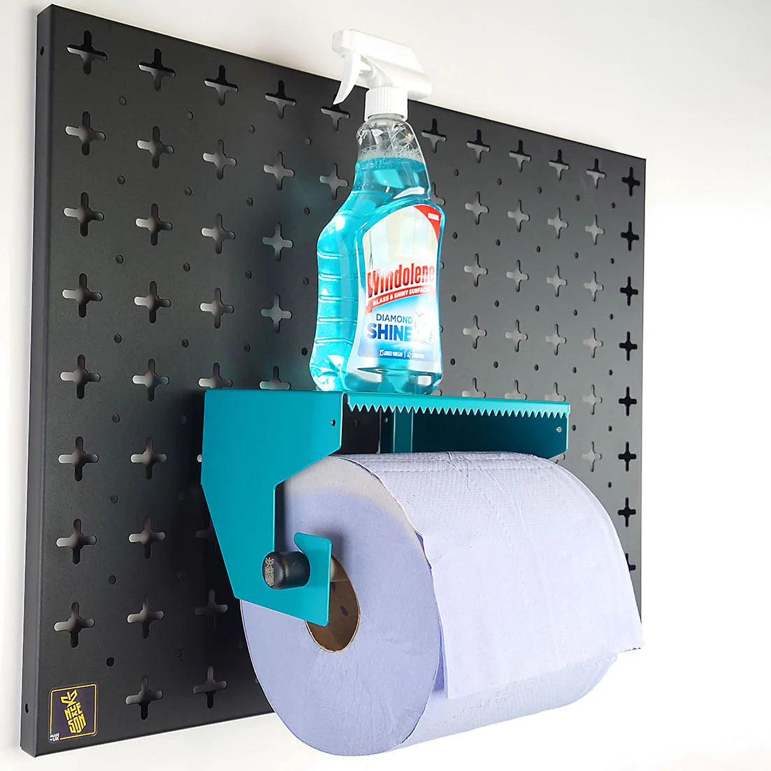 Pegboard Blue Roll Holder Shelf, in aqua blue with roll in holder and cleaning bottle on the shelf, mounted on a black pegboard wall organiser