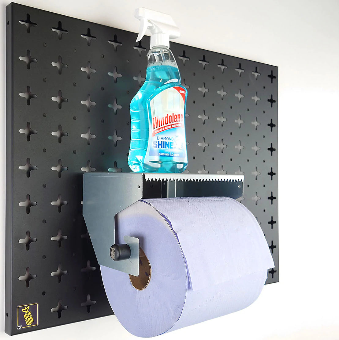 Pegboard Blue Roll Holder Shelf, in galvanised steel with roll in holder and cleaning bottle on the shelf, mounted on a black pegboard wall organiser