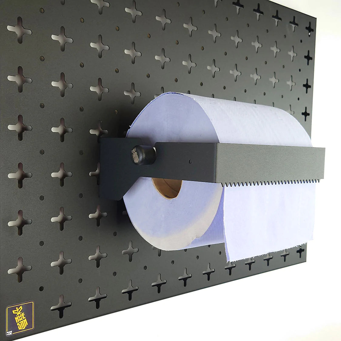 A Black, blue roll holder with a blue roll in it, mounted on a black wall, designed to be used with Nukeson Tool Wall Organiser Panels.